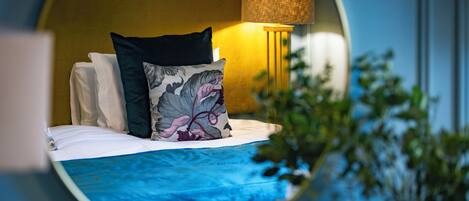 A circular view of a hotel room with a bed, pillows, a lamp, and a plant.