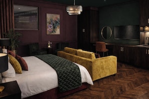 A hotel room with a bed, a sofa, a television, and a mirror. - Sweeney Inverness (Inverness)