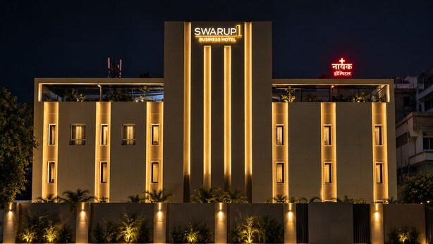 Un edificio moderno con un cartello ben visibile per 'SWARUPI BUSINESS HOTEL' e un cartello nelle vicinanze per 'NAYYAK HOSPITAL'.