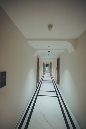 A long, narrow hotel corridor with a marble floor, white walls, and doors on both sides. - Swarup1 Business Hotel (Jabalpur, Madhya Pradesh)