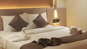 Camera d'albergo con un letto grande, una testiera con illuminazione integrata e un comodino con lampada.