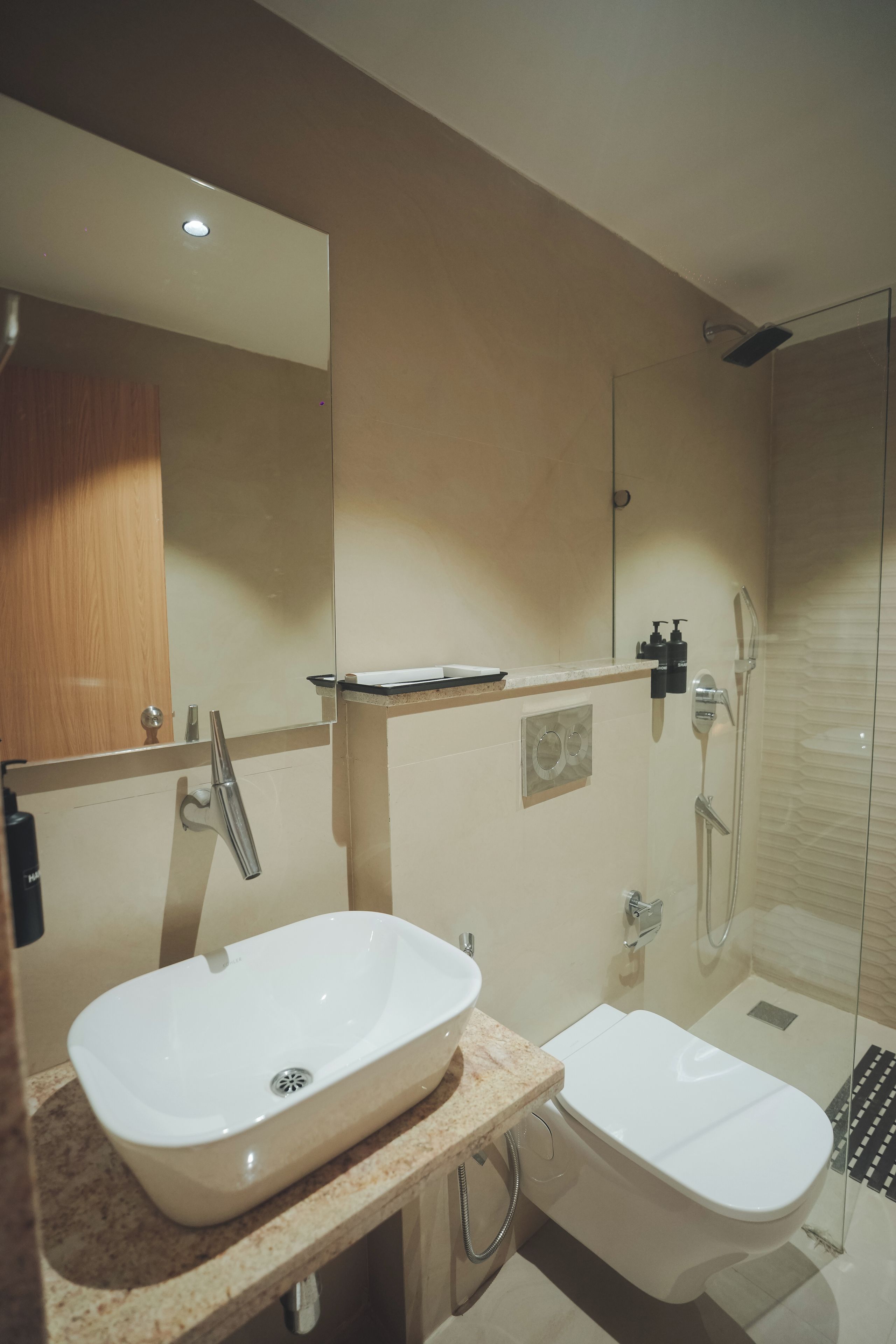 A modern bathroom with a large mirror, a sink, a bidet, and a shower.