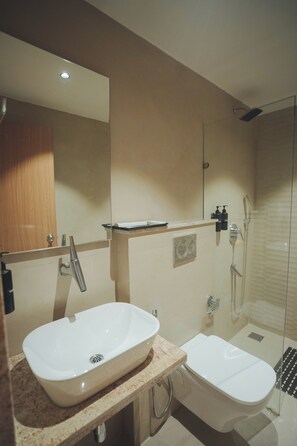 A modern bathroom with a large mirror, a sink, a bidet, and a shower. - Swarup1 Business Hotel (Jabalpur, Madhya Pradesh)