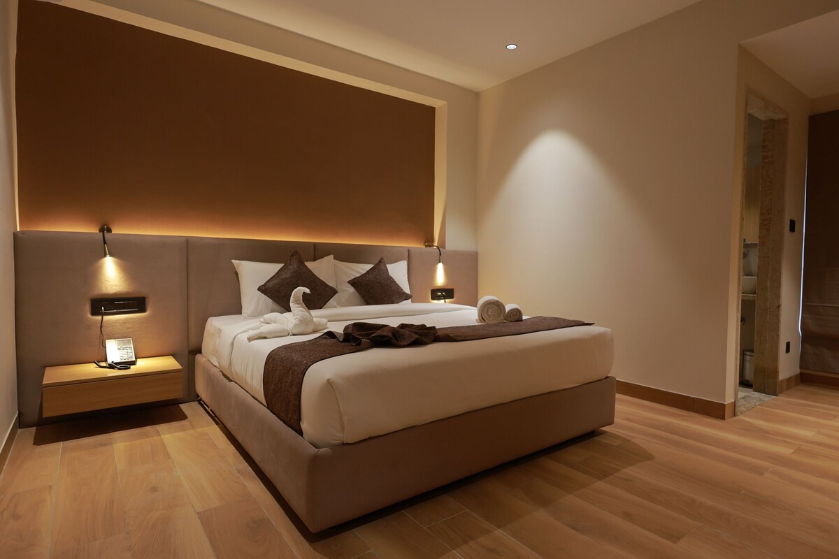 A modern bedroom with a large bed, bedside lamps, and a wooden floor.