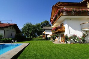 Ein Wohnhaus mit Schwimmbad, gepflegtem Rasen und einem Balkon mit Blumenkästen.
