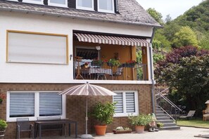 A two-story house with a balcony, outdoor seating, and potted plants. - Holiday apartment with 1 bedroom (Brodenbach)