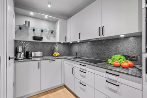 A modern kitchen with white cabinets, a granite countertop, and stainless steel appliances. - Haus Elisabeth, Apartment 10, on the beach with parking, Wi-Fi, and a balcony (Sylt)