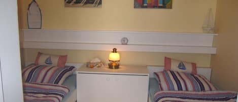 Et værelse med to senge, et natbord med lampe og to billeder på væggen.