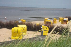 A beach with yellow numbered beach huts and a sandy shoreline. - Residence Naturdüne Holiday Apartment No. 5 (Cuxhaven Duhnen)