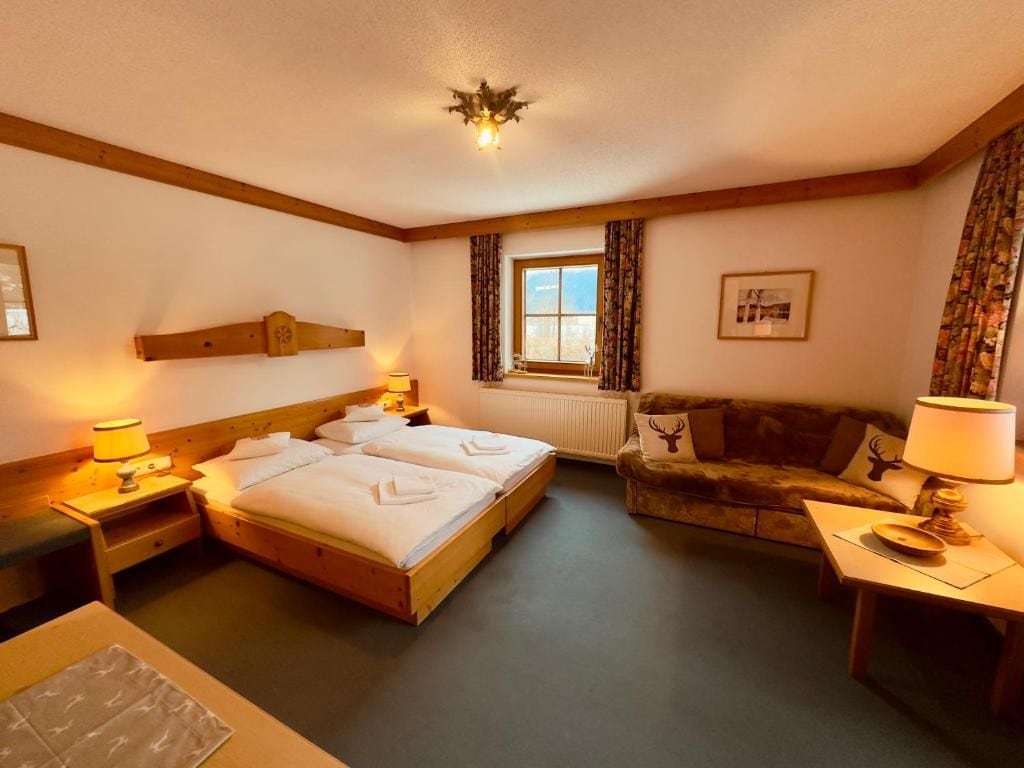 Een hotelkamer met een tweepersoonsbed, een slaapbank, een tafeltje en een raam met gordijnen.