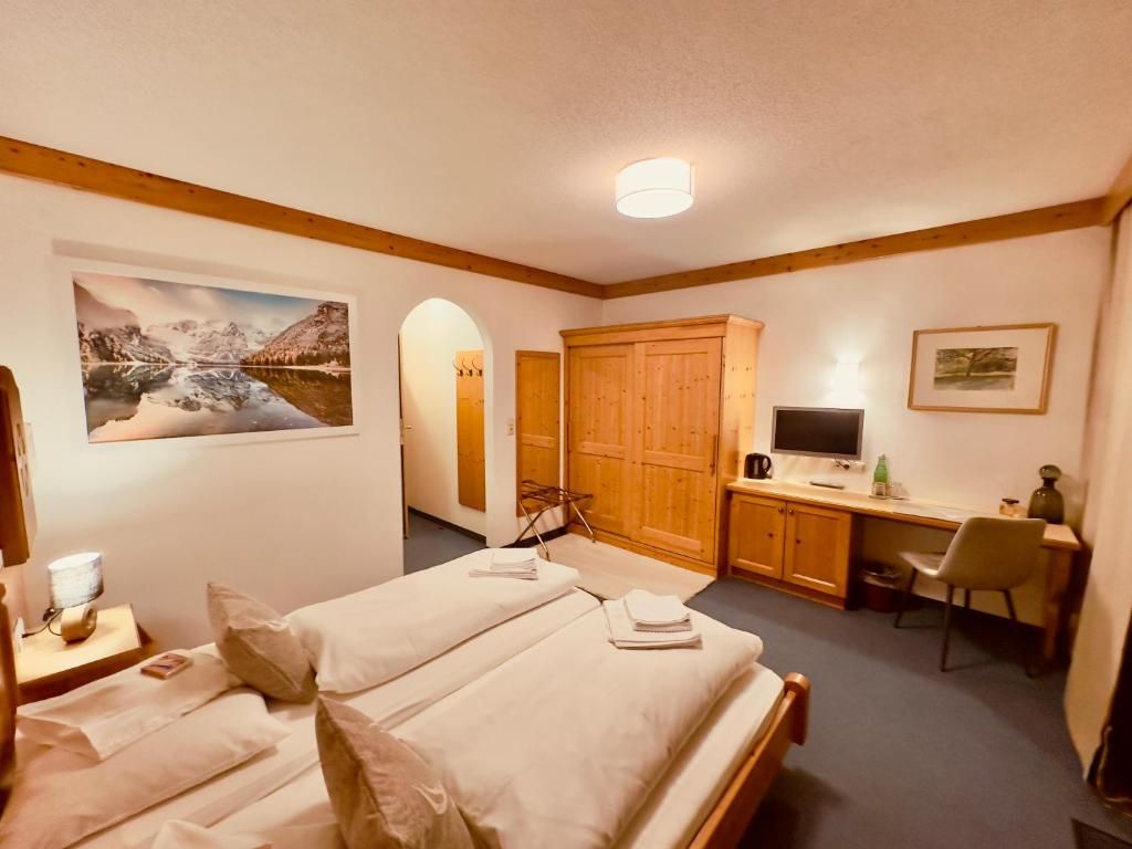 Habitación de hotel con dos camas, un escritorio, un televisor y un ventanal grande.