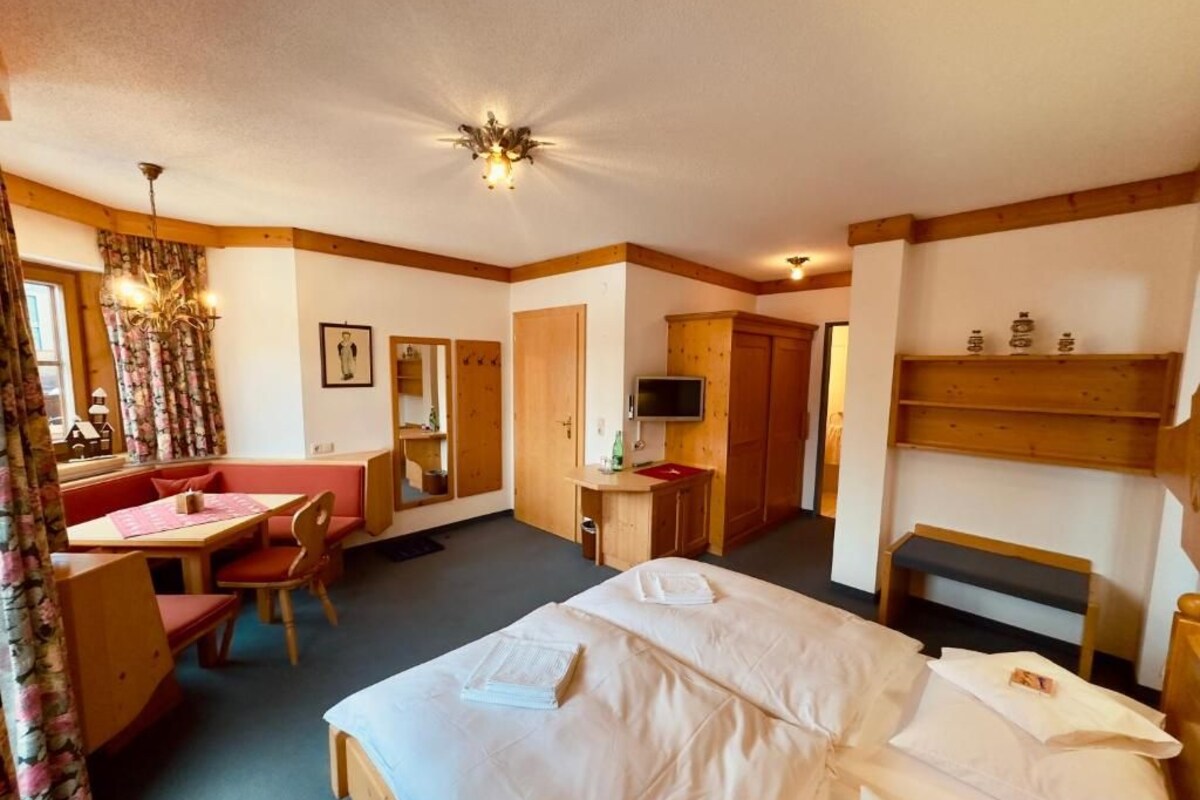 Ein Hotelzimmer mit einem Bett, einem Schreibtisch, einem Stuhl, einem Fernseher und einem Fenster mit Vorhängen.