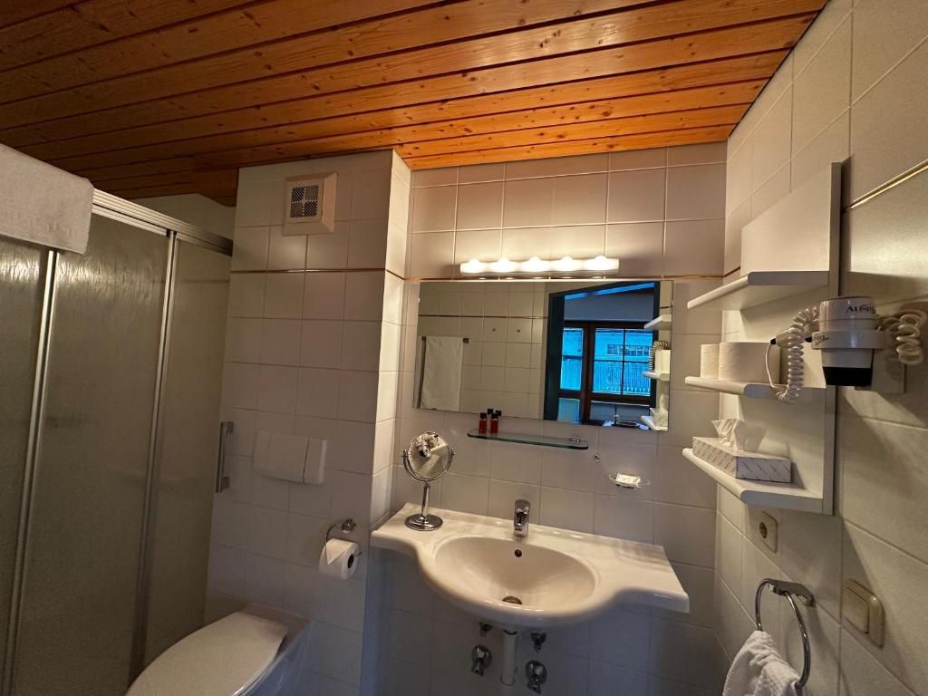 Ein Badezimmer mit Holzboden, einem weißen Waschbecken, einem Spiegel und einer Duschkabine.