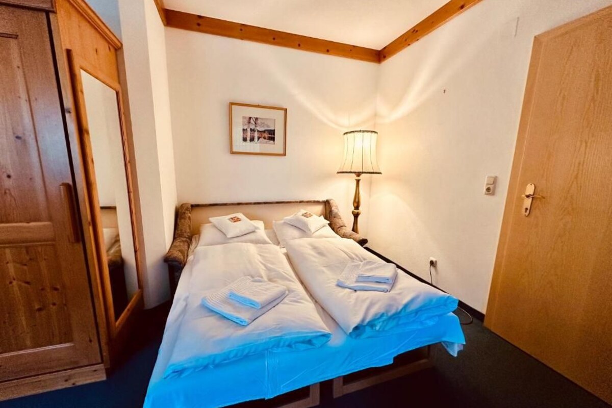 Ein Hotelzimmer mit einem Bett, einem Holzschrank, einer Lampe und einer Tür.