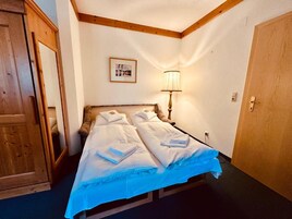Una habitación de hotel con una cama, un armario de madera, una lámpara y una puerta.