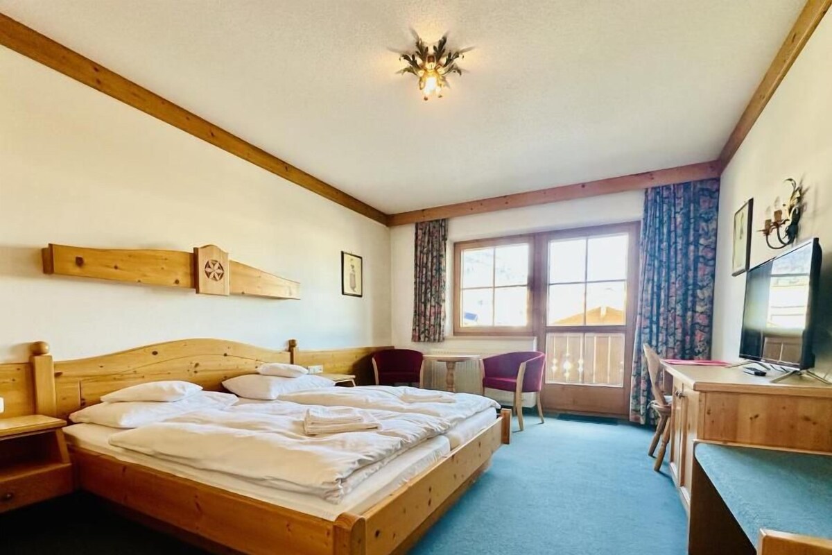 Ein Hotelzimmer mit einem hölzernen Bett, einem Schreibtisch, einem Stuhl und einem Fernseher.