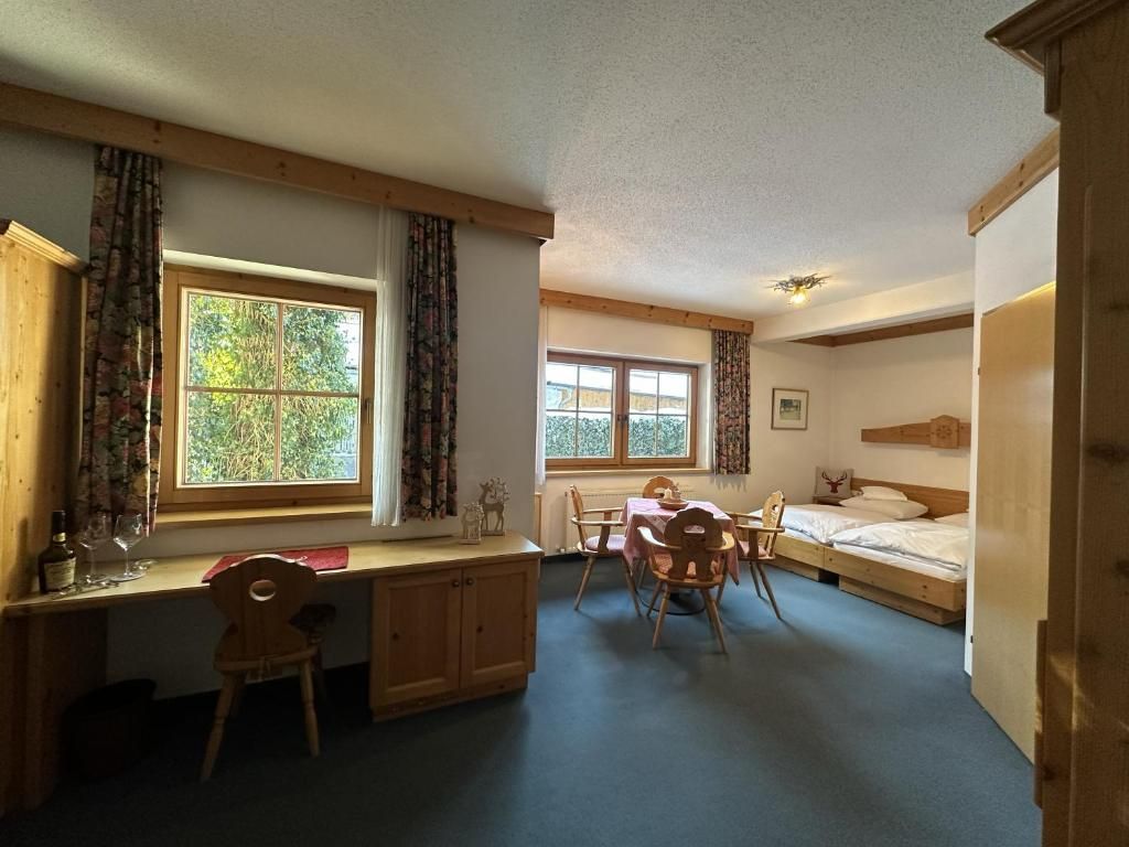 A room with a desk, two windows, a bed, and a chair.
