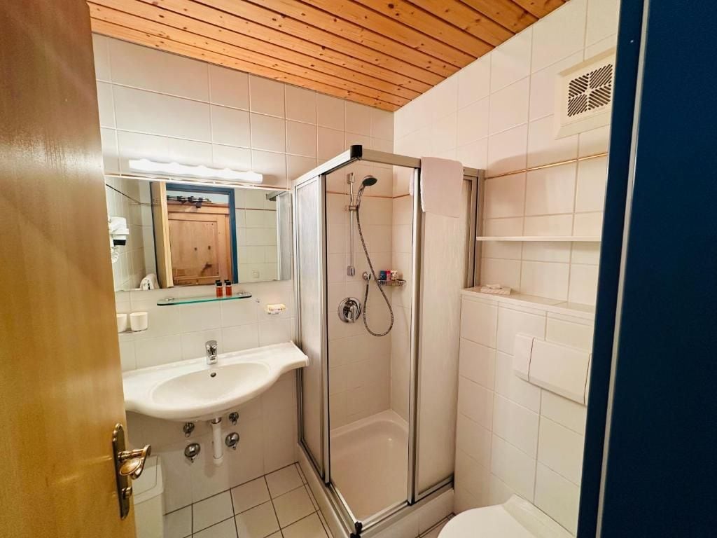 A bathroom with a glass-enclosed shower, a sink, and a toilet.