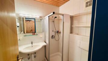 A bathroom with a glass-enclosed shower, a sink, and a toilet.