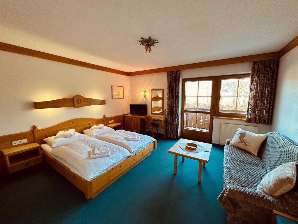Habitación de hotel con dos camas, un escritorio, una silla, una mesita y un sofá.