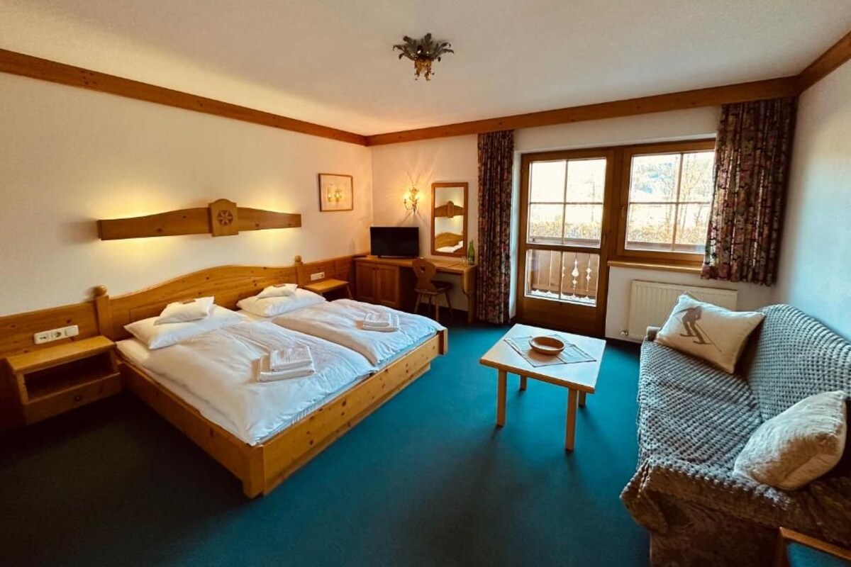 Ein Hotelzimmer mit zwei Betten, einem Schreibtisch, einem Stuhl, einem kleinen Tisch und einem Sofa.