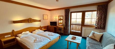 A hotel room with two beds, a desk, a chair, a small table, and a sofa.