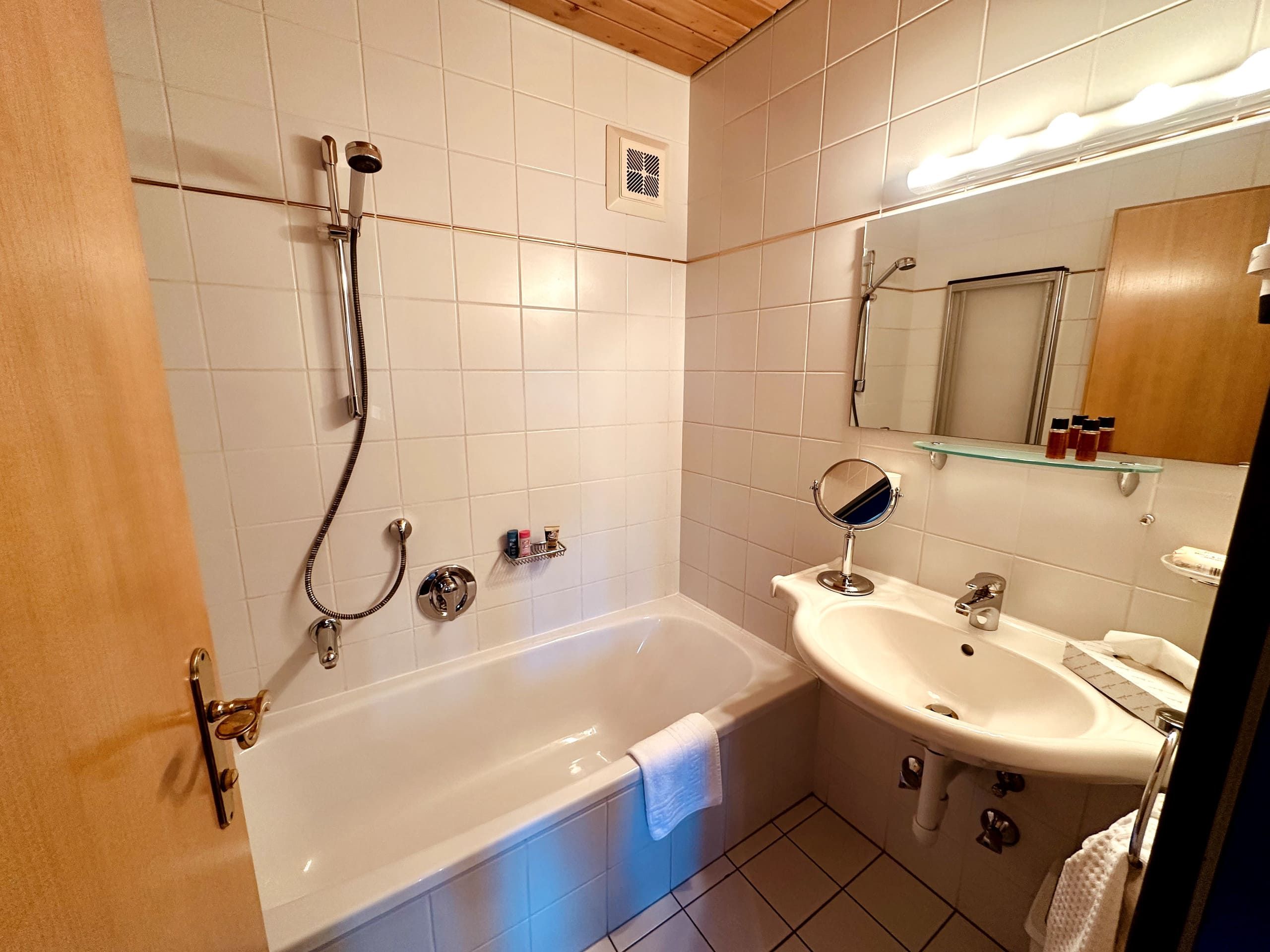 Un baño con bañera, lavabo, espejo y ducha.