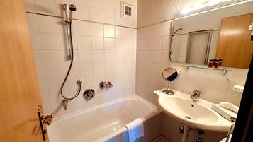 Un baño con bañera, lavabo, espejo y ducha.