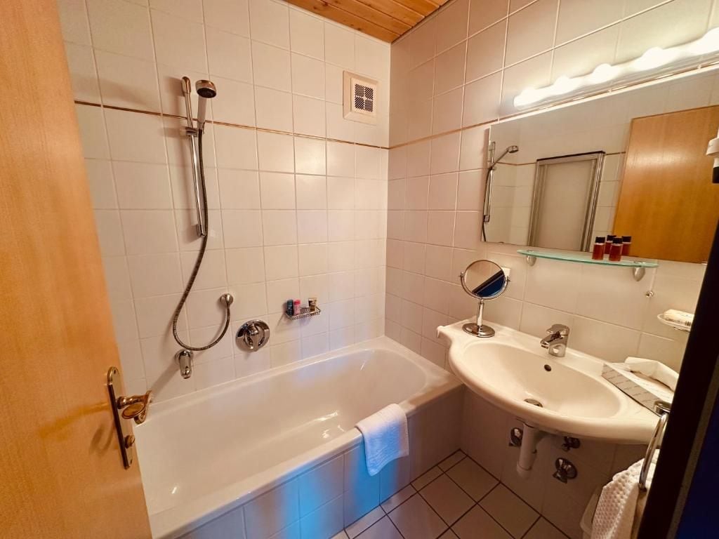 Ein Badezimmer mit einer Badewanne, einem Waschbecken und einem Spiegel.