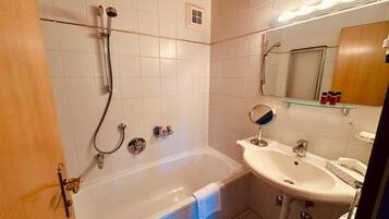 Ein Badezimmer mit einer Badewanne, einem Waschbecken und einem Spiegel.