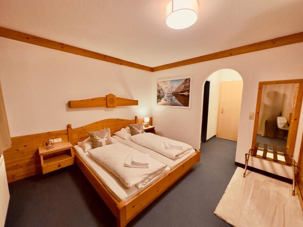 Una habitación con una cama de madera, una mesita de noche, un espejo y un cuadro en la pared.