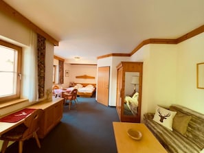 Ein Zimmer mit einem Bett, einem Schreibtisch, einem Stuhl, einer Couch und einem Spiegel.