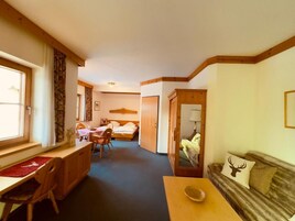 Una habitación con cama, escritorio, silla, sofá y espejo.