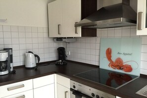 Eine Küche mit weißen Schränken, einer Edelstahl-Dunstabzugshaube, einer Kaffeemaschine und einem Schild mit Hummer-Motiv.