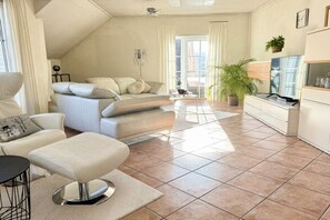 A modern living room with a sofa, ottoman, and a television. - Holiday apartment with 2 bedrooms (Bad Harzburg)