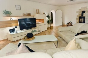 Ein modernes Wohnzimmer mit Flachbildfernseher, einer Couch, einem Couchtisch und einem Kamin.