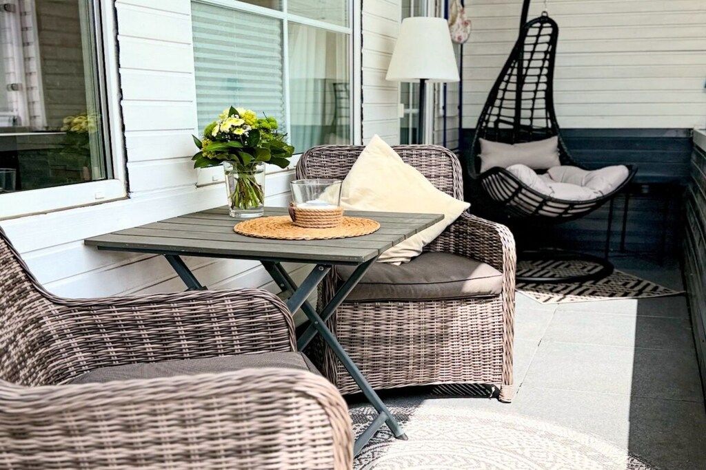 A wicker outdoor seating area with a table, chairs, and a hanging chair.