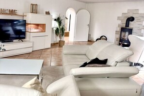 Ein modernes Wohnzimmer mit einer Couch, einem Flachbildfernseher, einem weißen Schrank und einem Kamin.