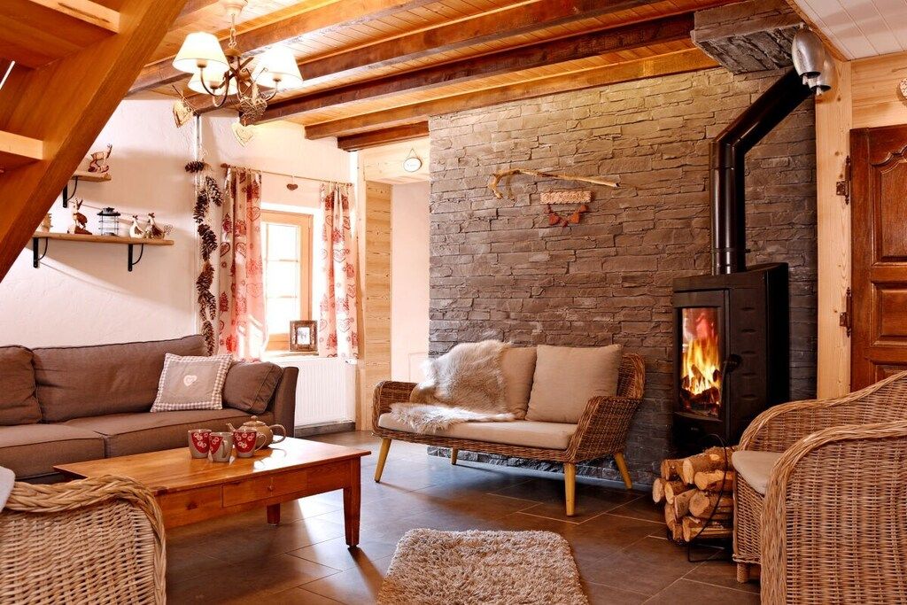 A cozy living room with a stone wall, a fireplace, and wicker furniture.