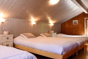 Une chambre avec trois lits en bois, chacun accompagné d’une table de chevet assortie et d’un petit objet décoratif.