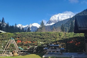 A mountain landscape with a wooden swing set and picnic table in a garden area.