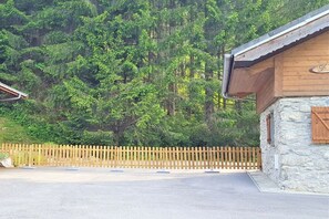 A stone building with a wooden door and a metal roof, surrounded by a wooden fence and dense forest. - Alpine hut in CHATEL with barbecue (CHATEL)