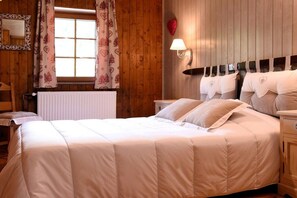 A bedroom with a large bed, wooden walls, a window with curtains, a bedside lamp, and a heart-shaped decoration. - Alpine hut in CHATEL with barbecue (CHATEL)