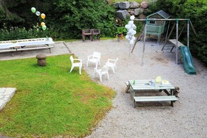 Un espace de jeux pour enfants avec des balançoires, un toboggan et une table de pique-nique.