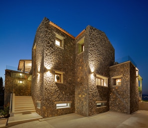 A modern stone building with multiple windows and a staircase leading to the entrance. - Villa Nera Corfu (Kerkira)