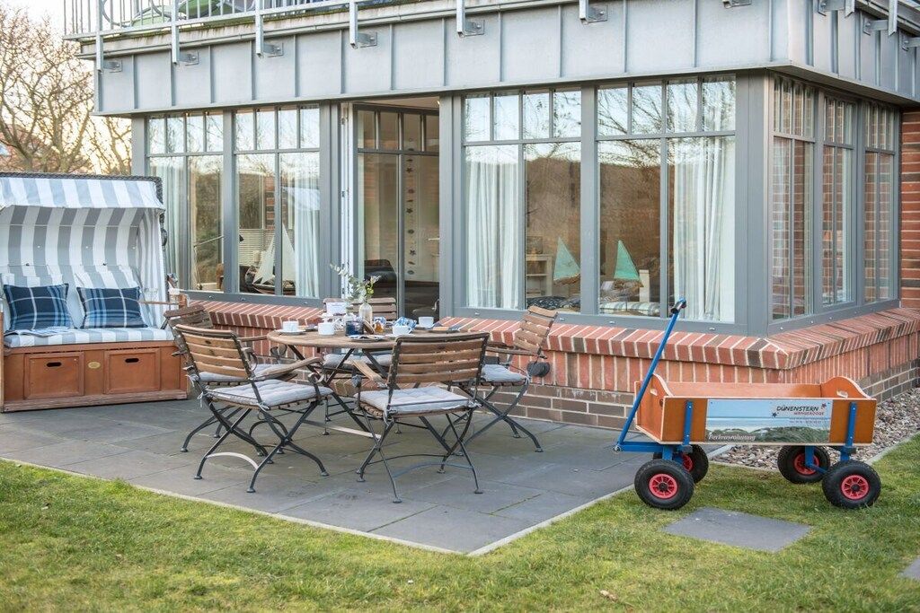 Eine Terrasse im Freien mit einem Esstisch, Stühlen und einer überdachten Sitzgelegenheit.