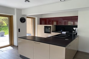 Een moderne keuken met een centraal eiland, ingebouwde apparatuur en uitzicht op het buiten.