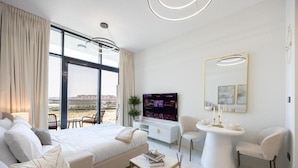 Een moderne hotelkamer met een groot bed, een zithoek, een televisie en een eettafel.