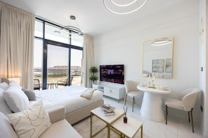 A modern hotel room with a large bed, a seating area, a television, and a dining table. - Bloomfields Studio in The Gate - Masdar (Abu Dhabi)