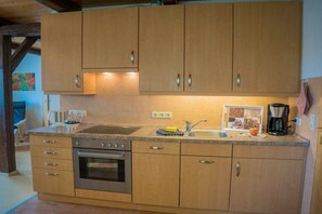 A kitchen with wooden cabinets, a stainless steel oven, a sink, and a coffee maker. - Holiday apartment in Fehmarn with Wi-Fi (Fehmarn)